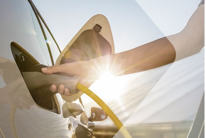 Eine Person hält einen Elektro-Lade-Stecker in der Hand und lädt damit ihr Elektro-Auto