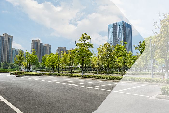 Parkplatz mit grünen Bäumen und Stadt im Hintergrund