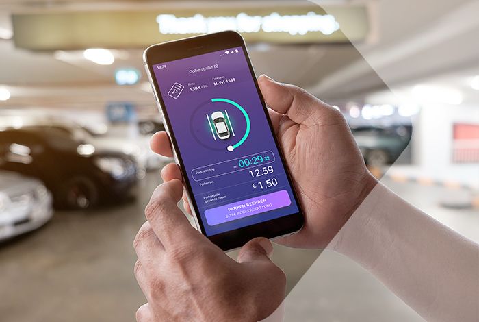 Eine Person hält ein Smartphone mit geöffneter PARCO App in einem Parkhaus